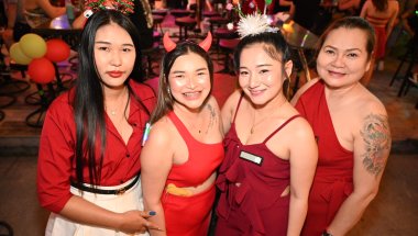 DZ6_2301: Four friends in festive red outfits smile for the camera during a lively night out.